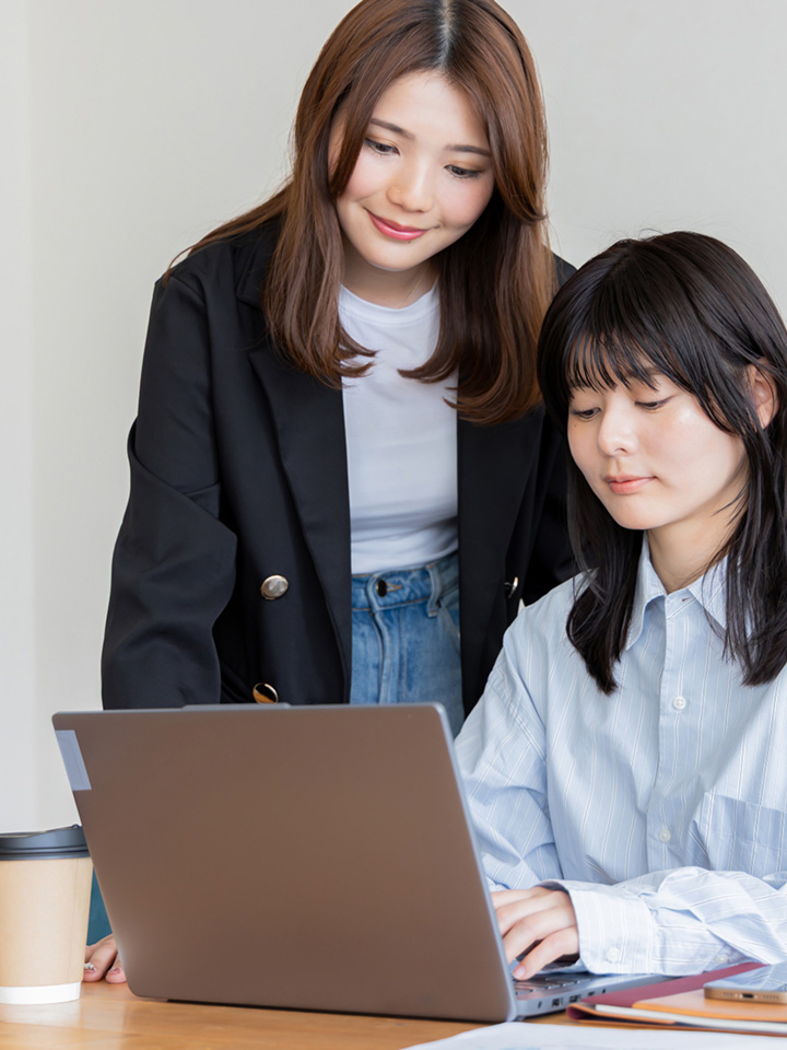 パソコンを触る女性と見守る女性